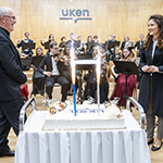 Jubileuszowy Koncert Orkiestry Symfonicznej i Chóru Educatus tort jubileuszowy z dyrygentami i orkiestrą w tle